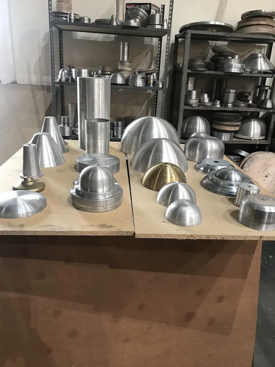 Assorted spun aluminum and brass domes, cones and cylinders on a work table